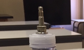 tappo della bottiglia di plastica bucato con infilata la valvola della camera d’aria di una bicicletta