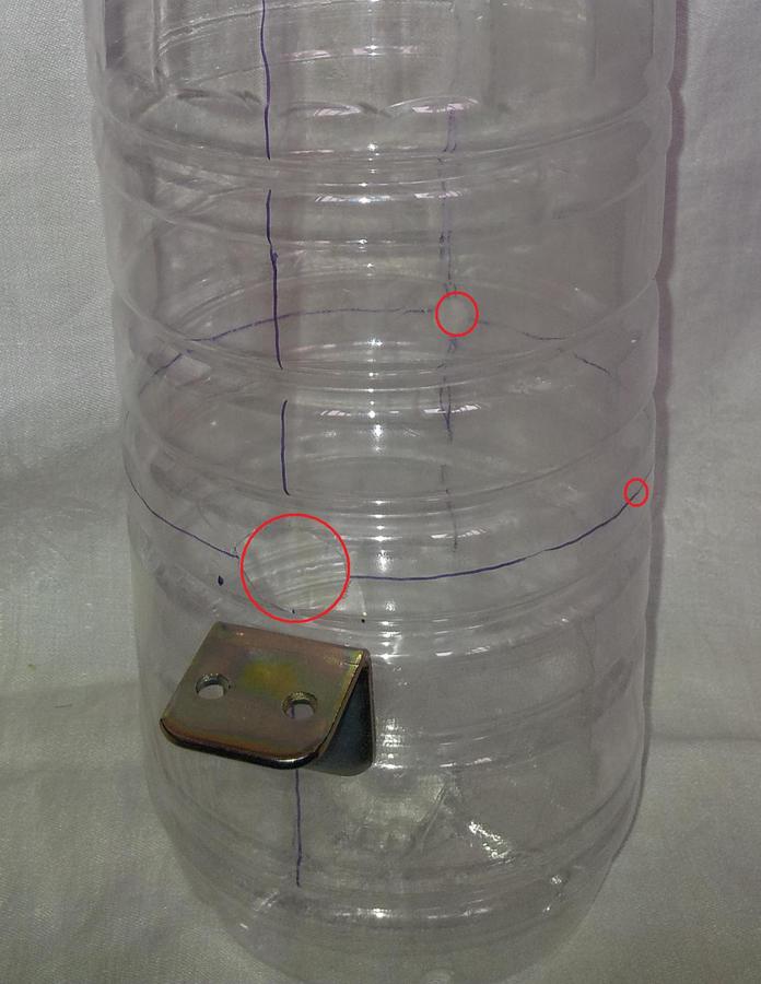 colonna isolante ricavata da una bottiglia di plastica, sono visibili i fori cerchiati in rosso e la lastrina angolare.